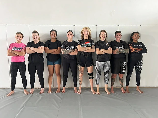 Members of the women's program lined up on the mats at Mission BJJ
